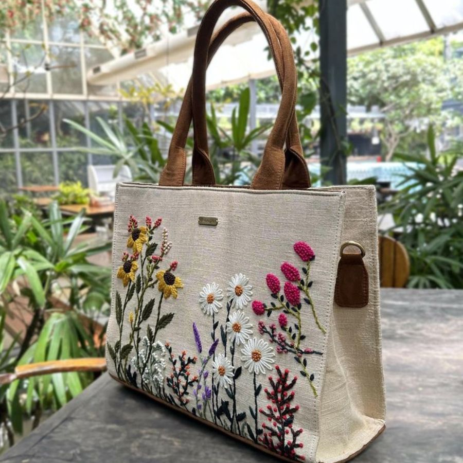 Handmade-Embroidered Bag Surrounded By Embroidery Threads and Sewing Tools in a Cozy Craft Studio